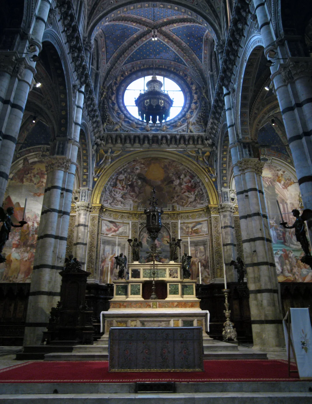 Interior of Siena Cathedral with striped marble columns and a decorated vaulted ceiling